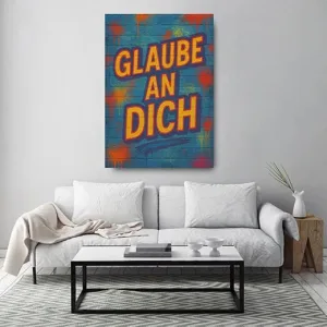 Kunstdruck glaube an dich – Leuchtend gelbe Buchstaben mit orangeroter Kontur formen „GLAUBE AN DICH“ auf einer petrolblauen Backsteinwand mit roten und orangefarbenen Sprühpunkten